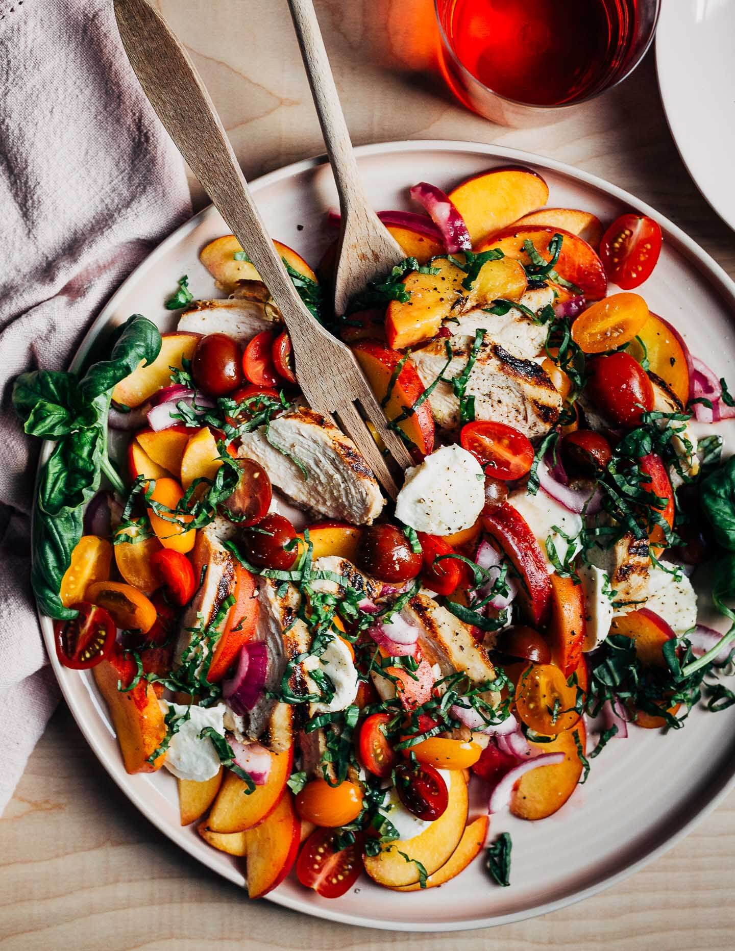 A platter with a peach and grilled chicken caprese salad