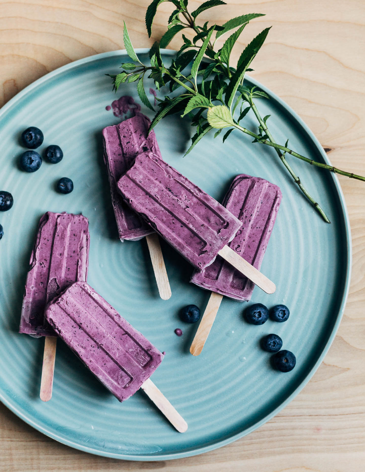 A plate with blueberry popsicles scattered on it. 