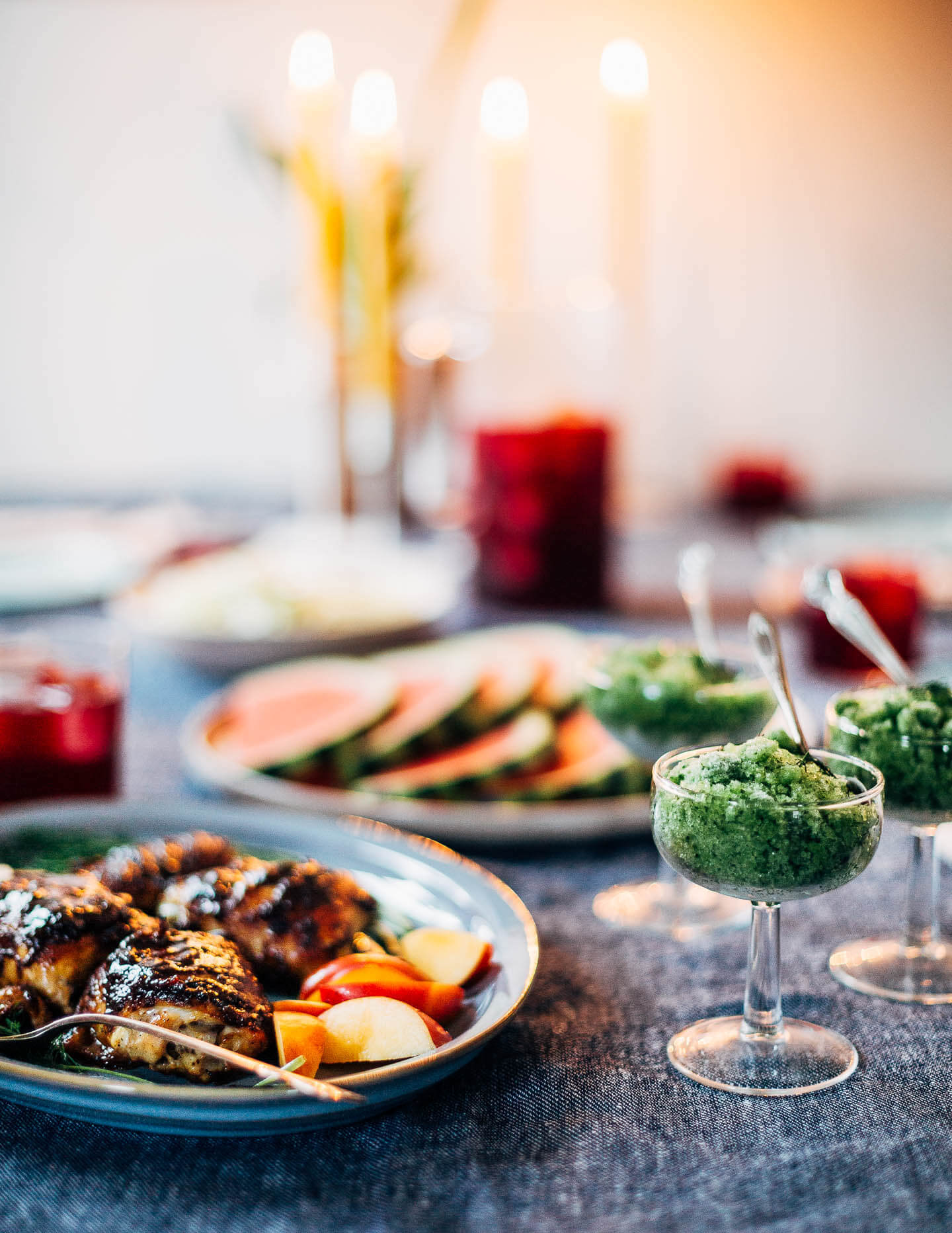 A table with candles and platters of food. 