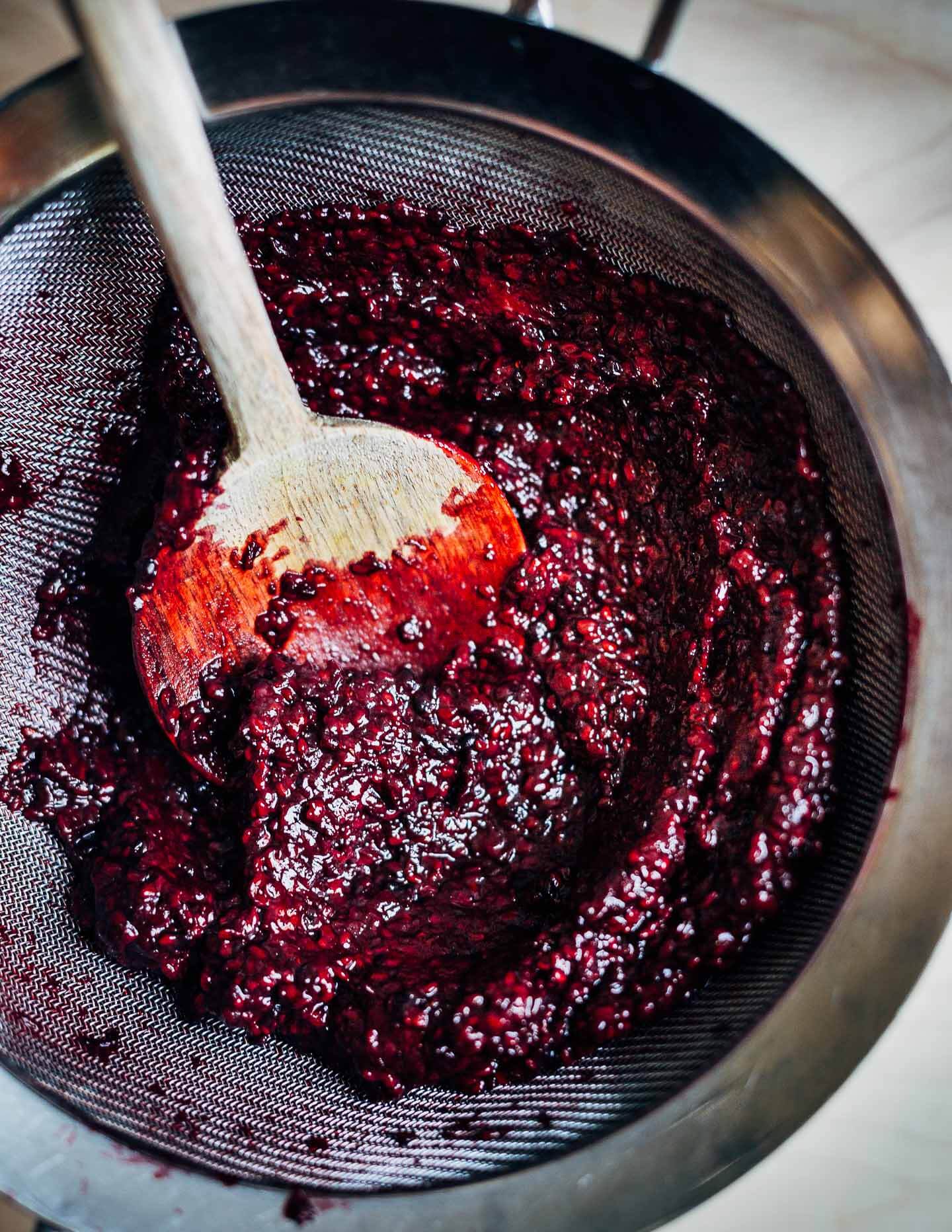 A mesh sieve and a pulpy mixture of berries. 