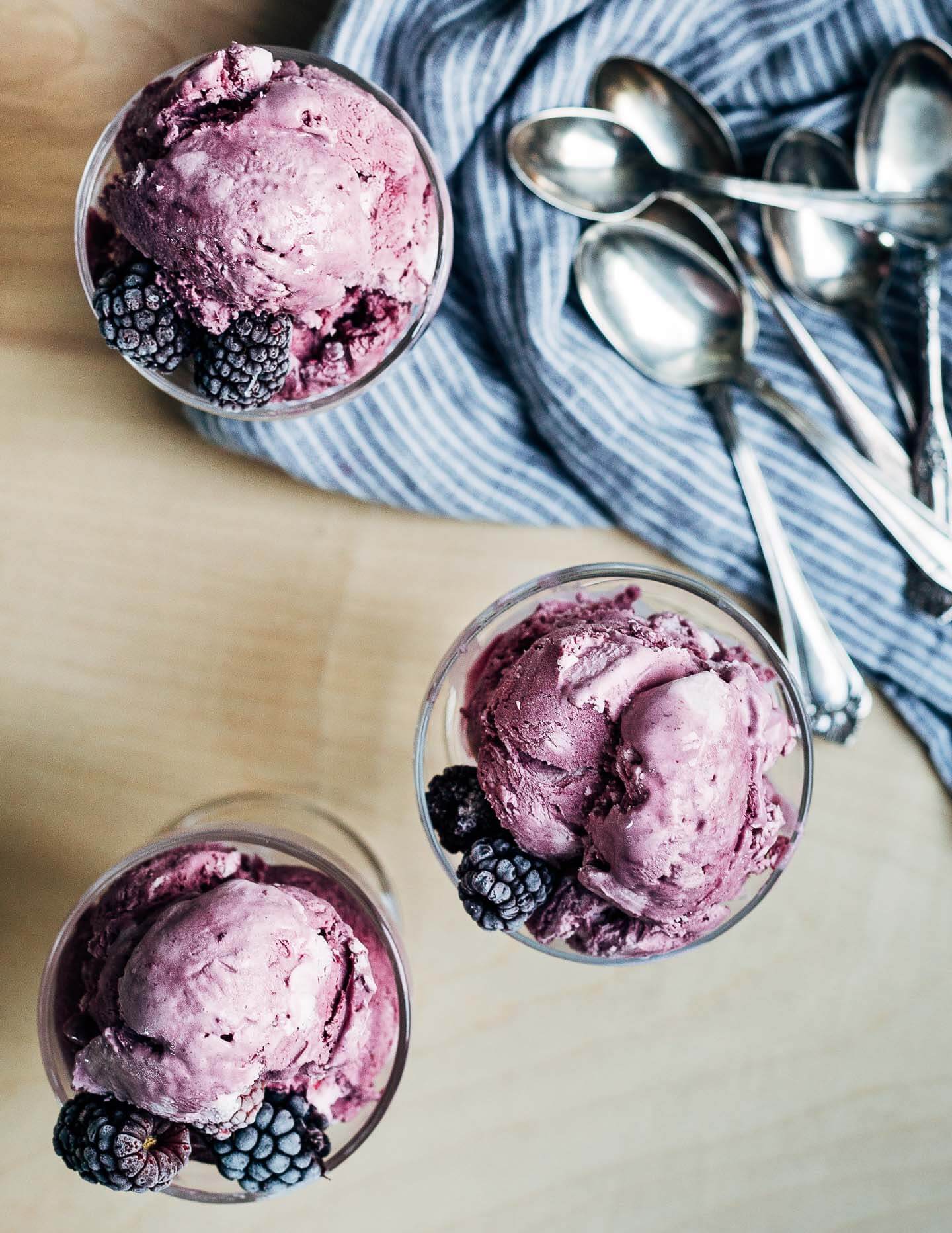 Dessert glasses filled with ice cream, with spoons and a napkin off to the side. 