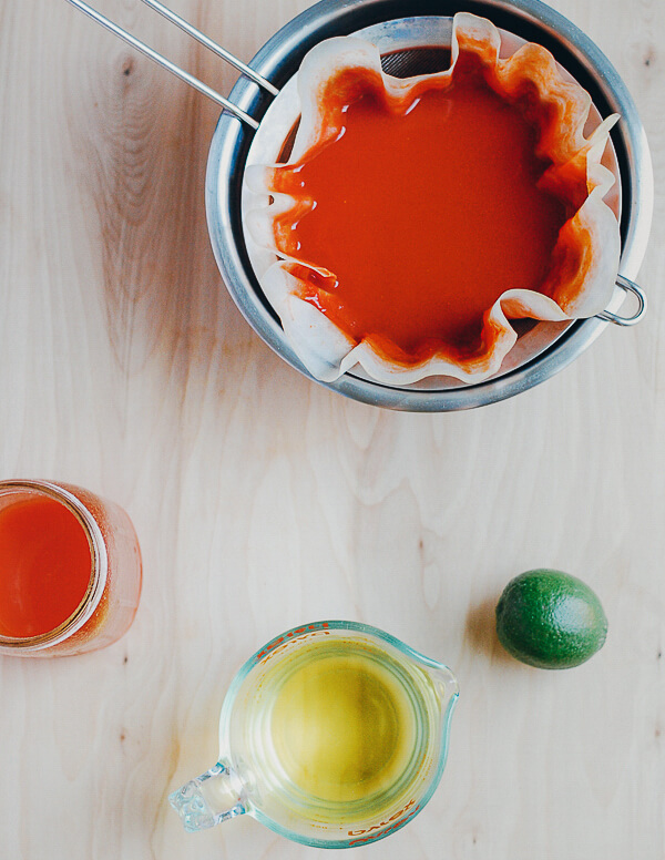 A strained with tomato juices and a measuring cup of clear tomato water. 