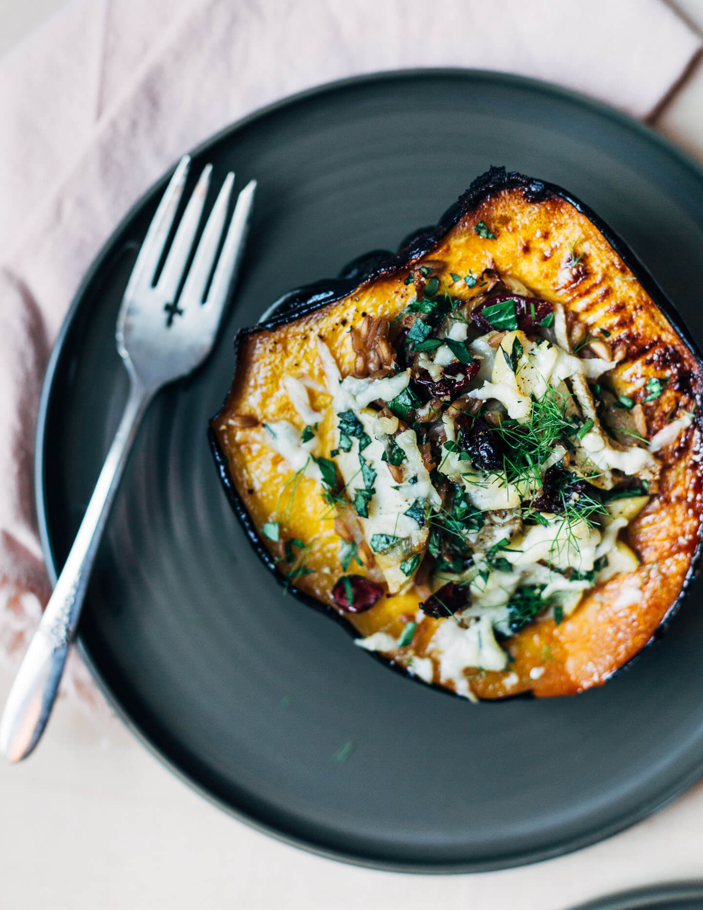 A stuffed acorn squash half served on a plate. 