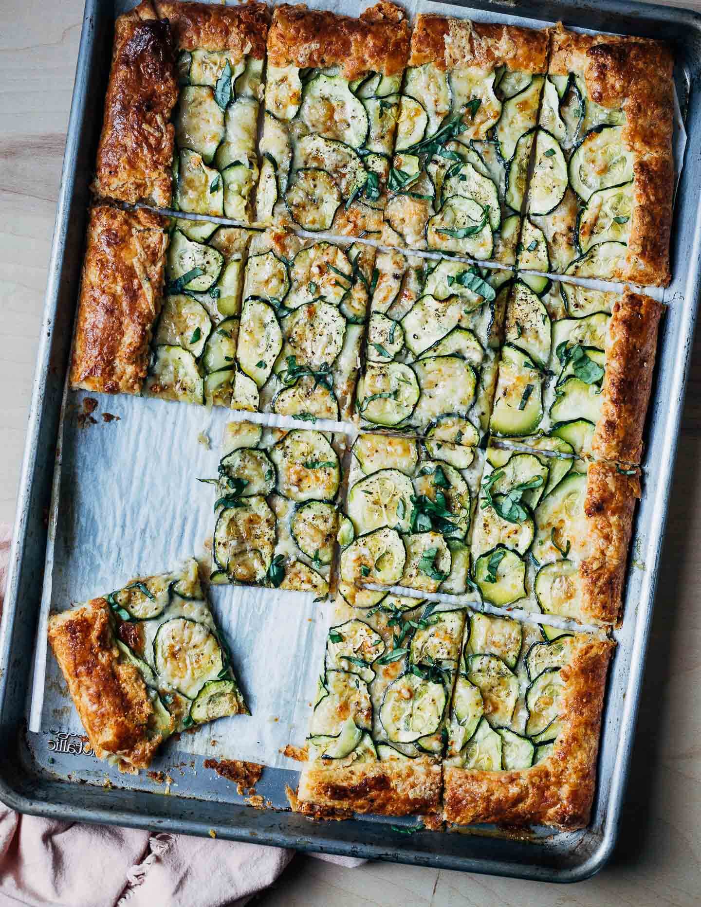 A sheet pan with a zucchini tart cut into squares. 