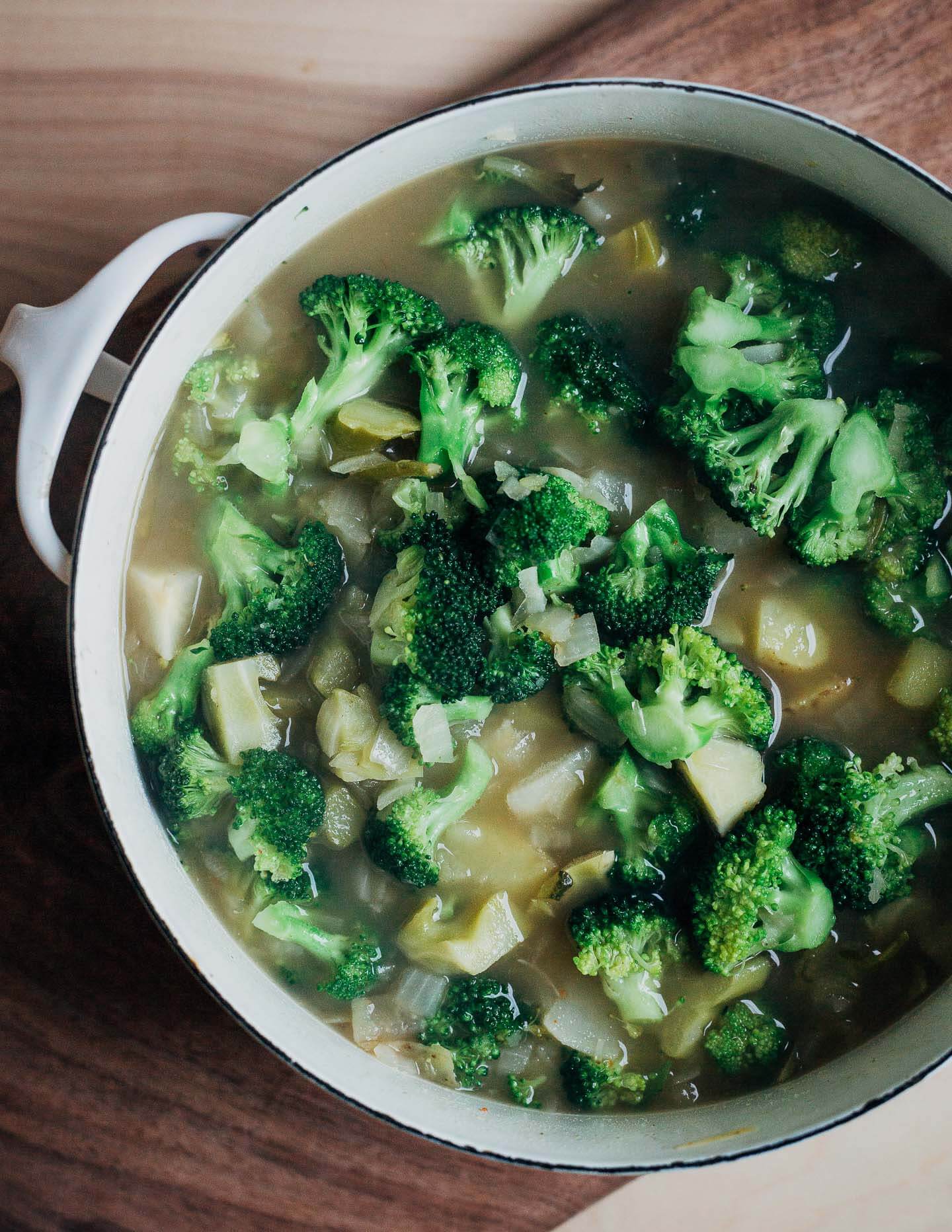 A soup pot with cooked broccoli and other vegetables. 