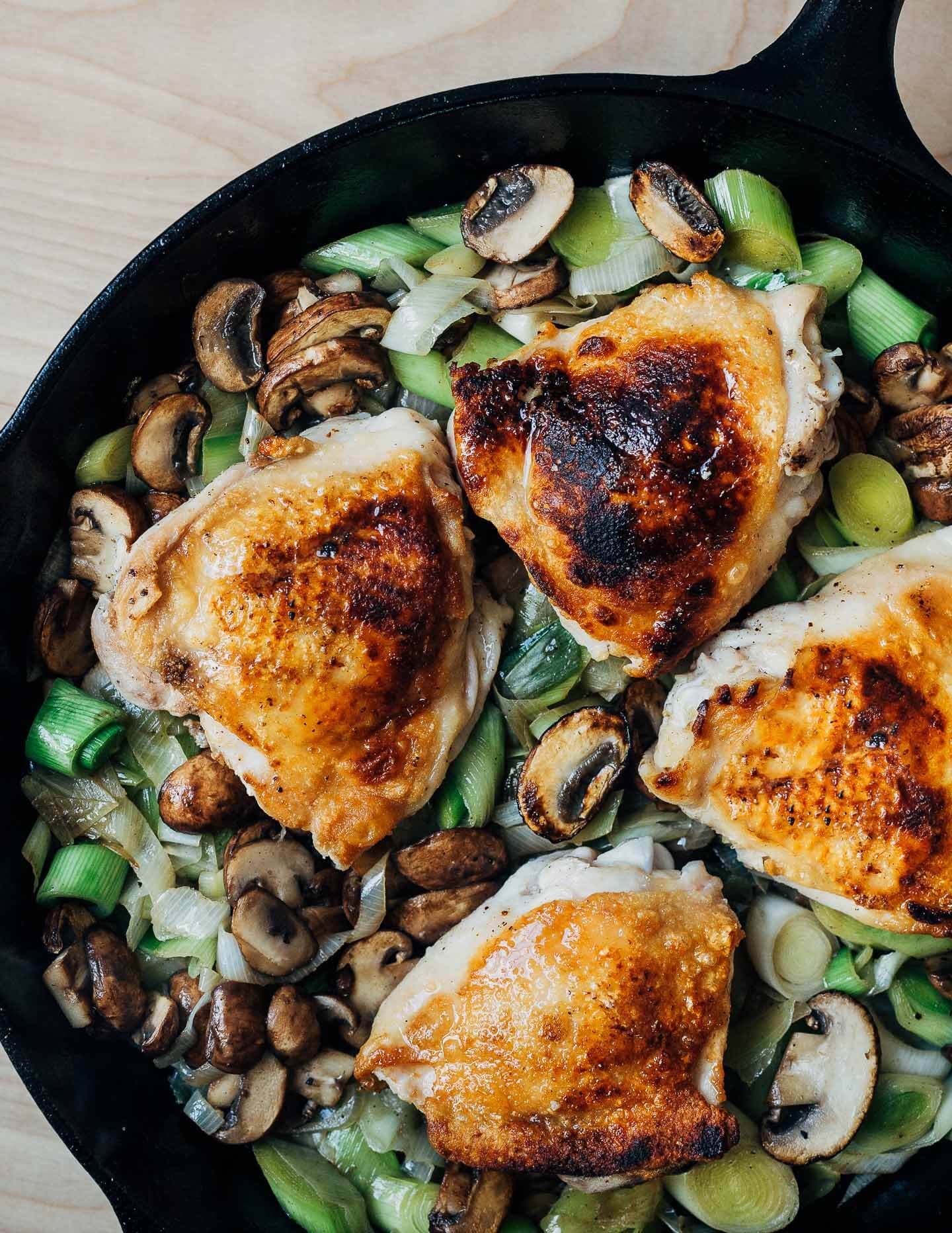 A skillet with seared chicken and vegetables, ready for the oven.