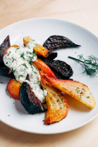 A plate with roasted beet wedges and yogurt sauce.