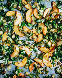 A sheet pan with shaved Brussels sprouts and sliced quince
