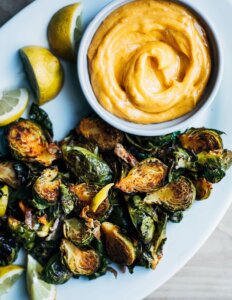 A plate of roasted Brussels sprouts with a little bowl of aioli.