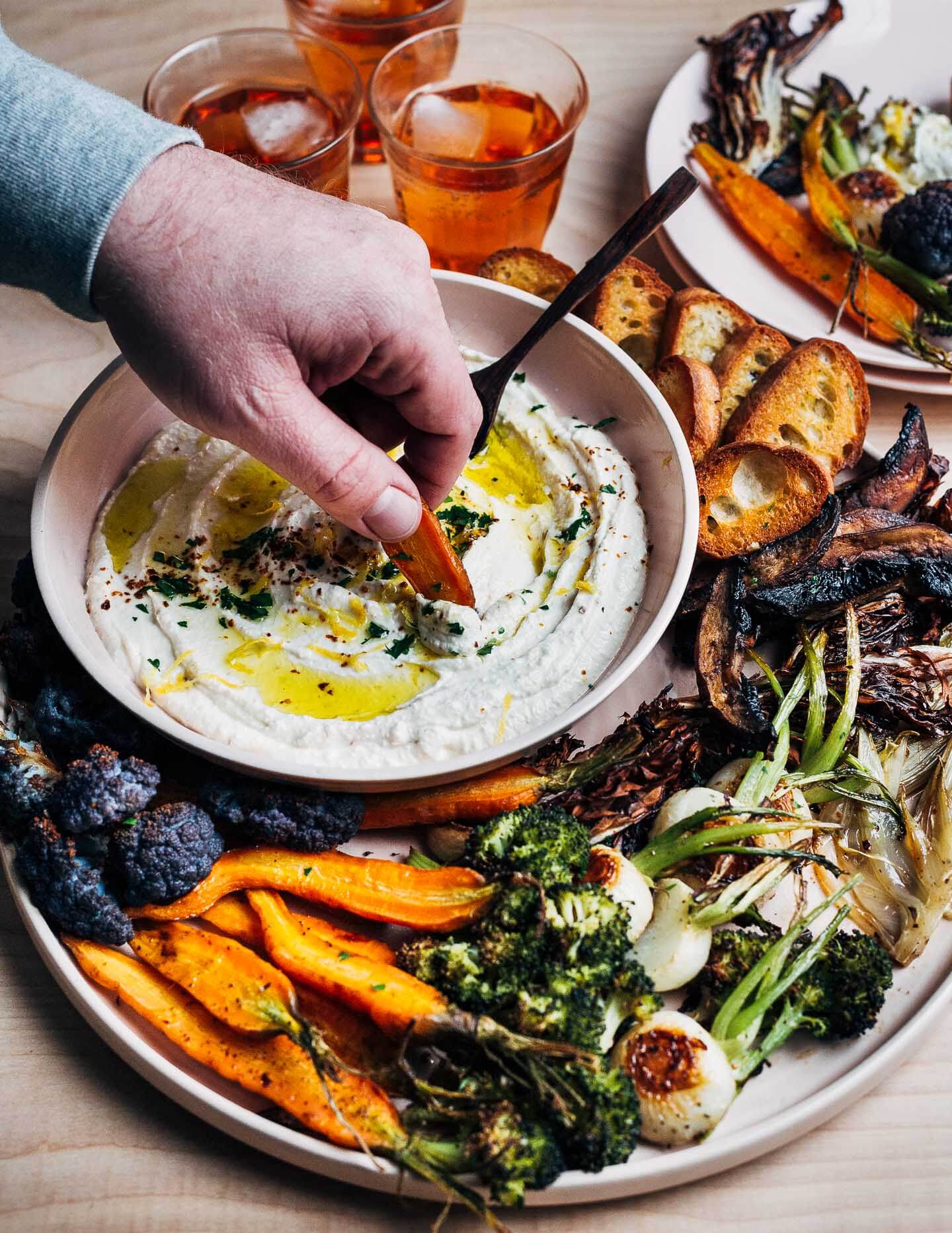 A hand dipping a carrot into whipped feta dip