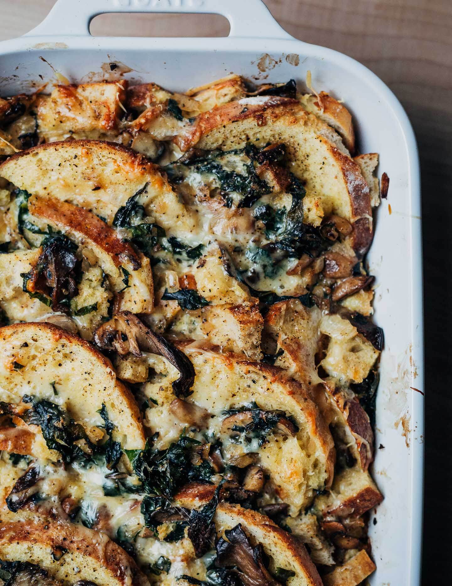 A baking dish with savory bread pudding and a dish cloth on the side. 