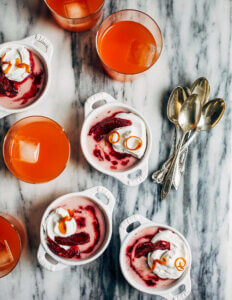 Little ceramic pots of panna cotta with a blood orange swirl, with glasses of fizzy soda and spoons alongside.
