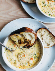 A bowl of creamy chowder with a couple slices of grilled bread on the side.