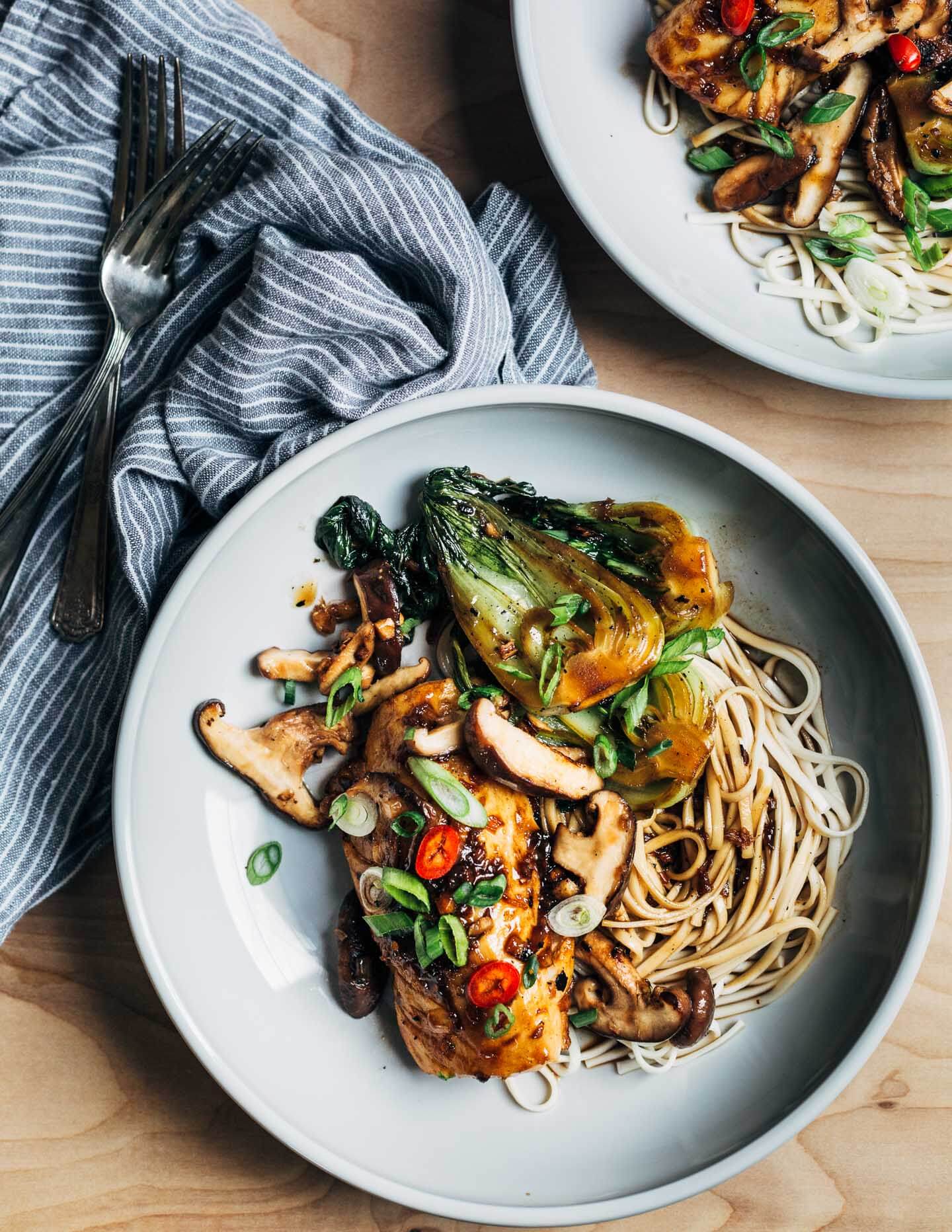 Glazed cod stir fry plated in two shallow bowls. 