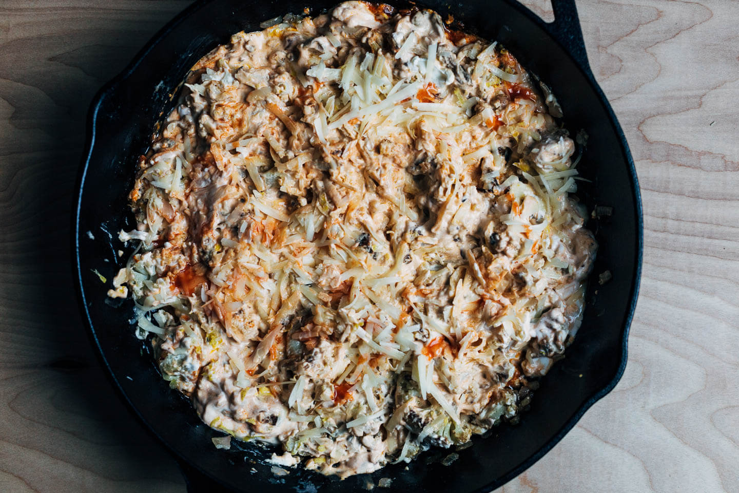 A skillet with Buffalo cauliflower dip, ready for the oven. 