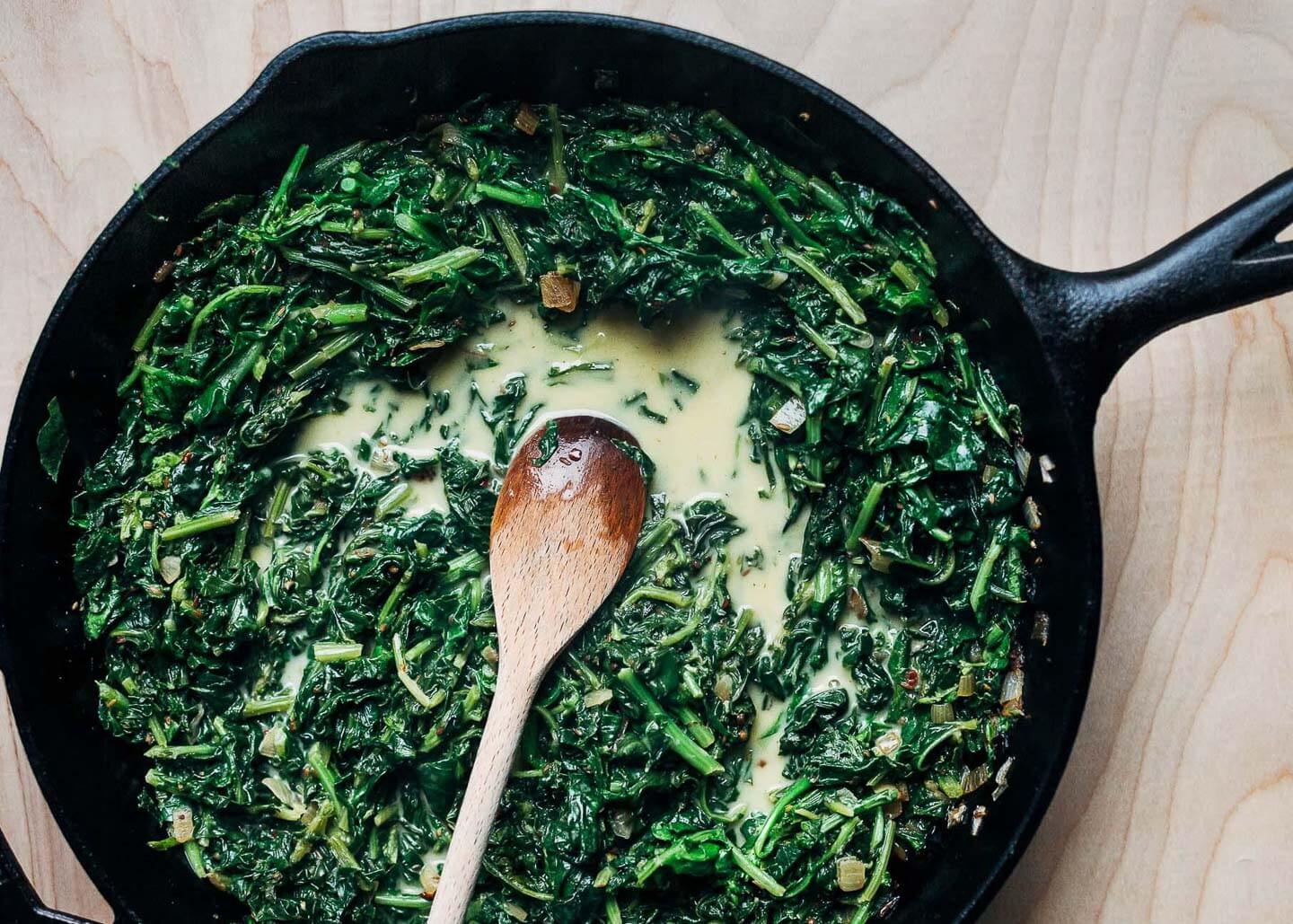 A skillet with braised collard greens in coconut milk. 
