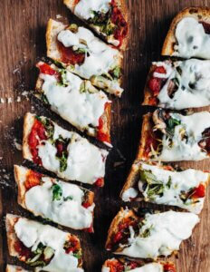 Two french bread pizzas on a cutting board