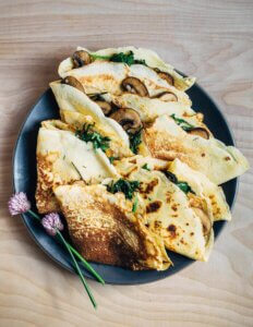 A serving plated piled with mushroom-filled crepes