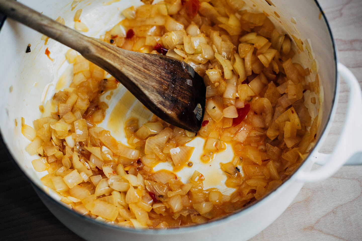 Onions cooking in a white soup pot. 