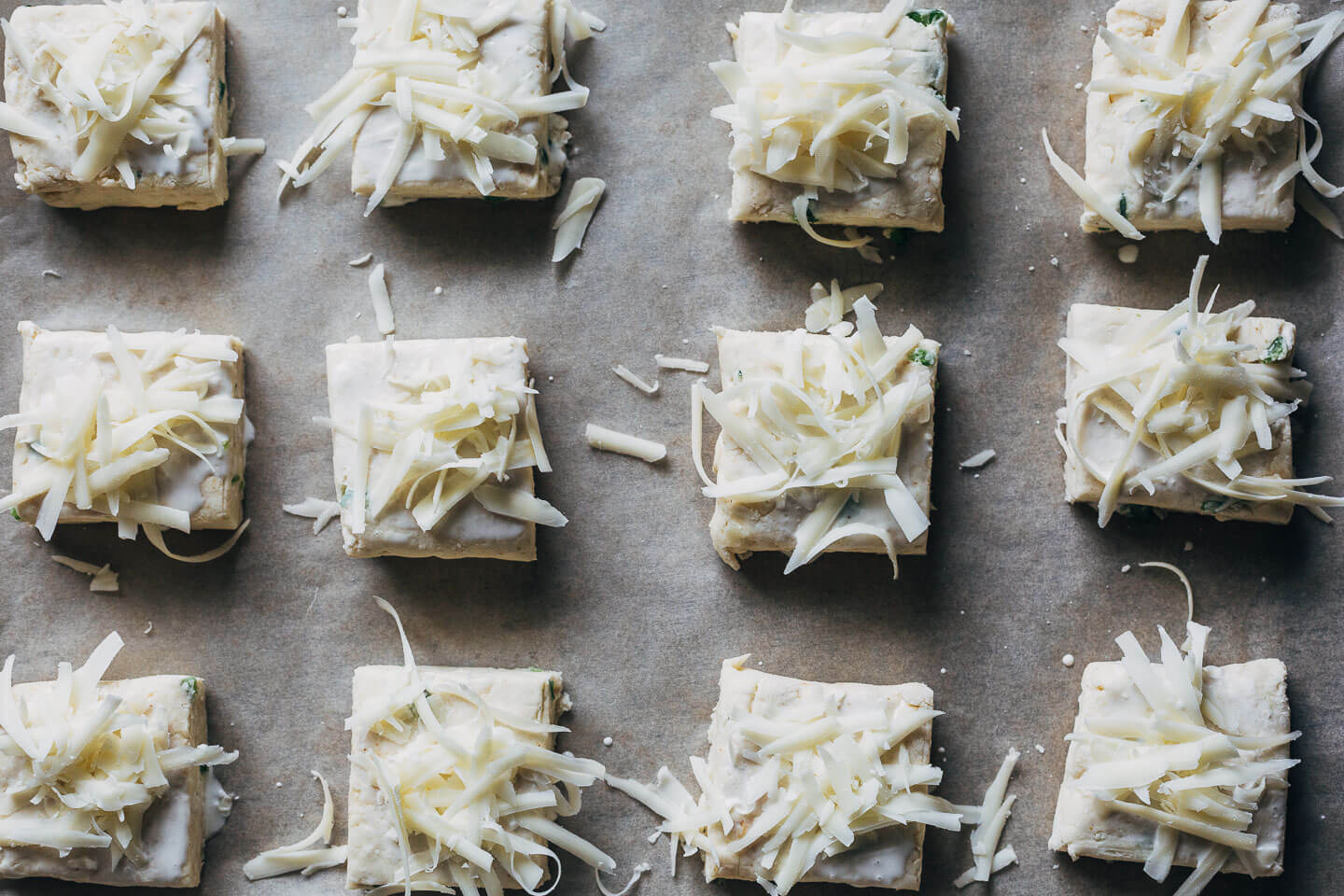 Uncooked biscuit squares with cheese, ready for the oven. 