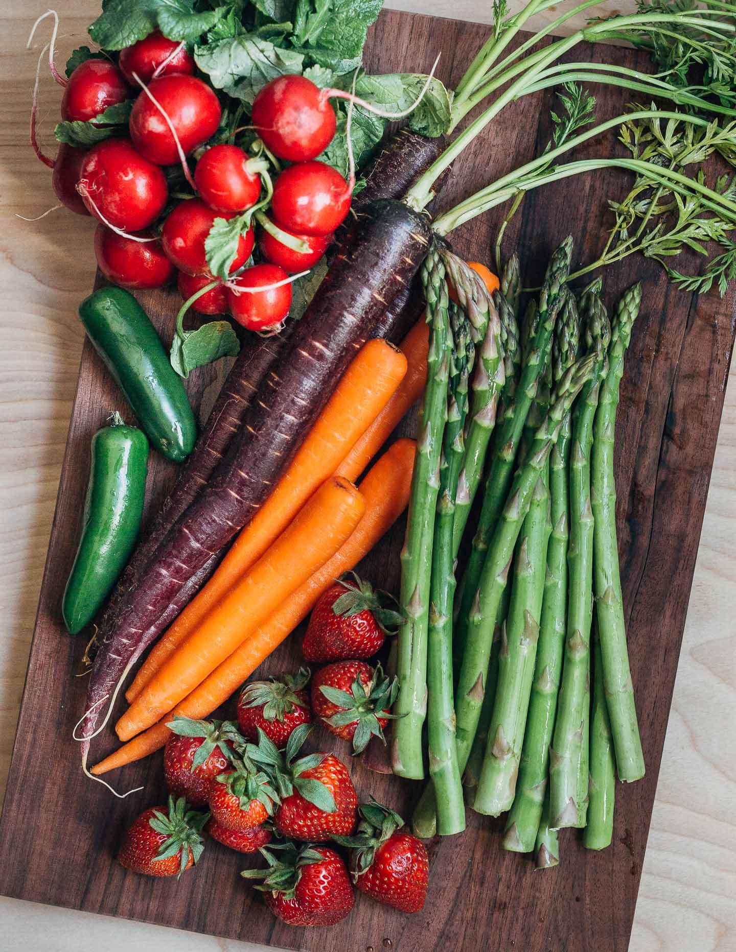 A cutting board with spring produce. 