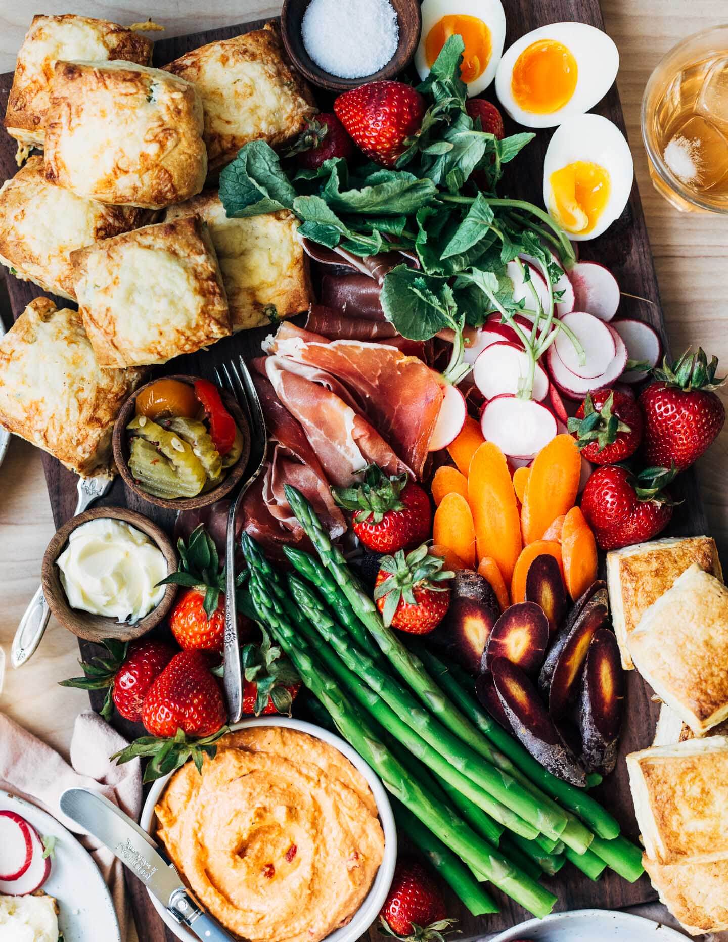 A board with biscuits, veggies, dips, and fixings. 