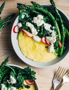 Bowls of polenta topped with asparagus, ricotta, and sliced radishes.