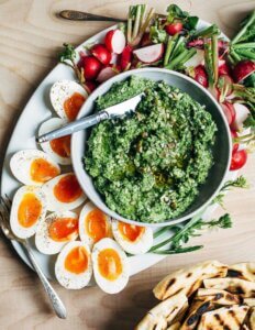 A platter of green garlic pesto with jammy eggs and sliced radishes alongside.