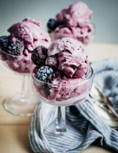 Parfait glasses filled with purple berry ice cream and frozen berries.