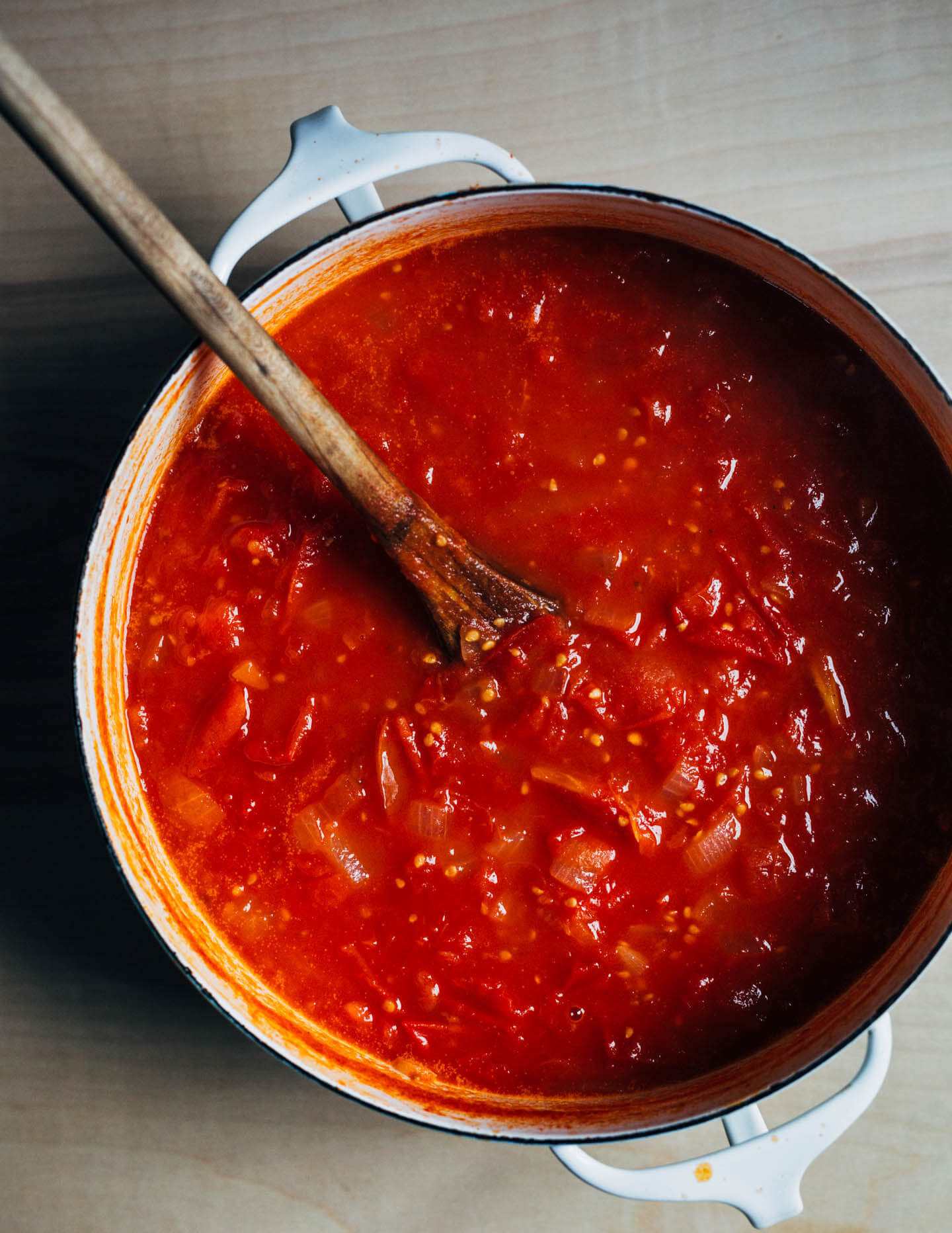 A pot with fresh tomato sauce and a wooden spoon. 