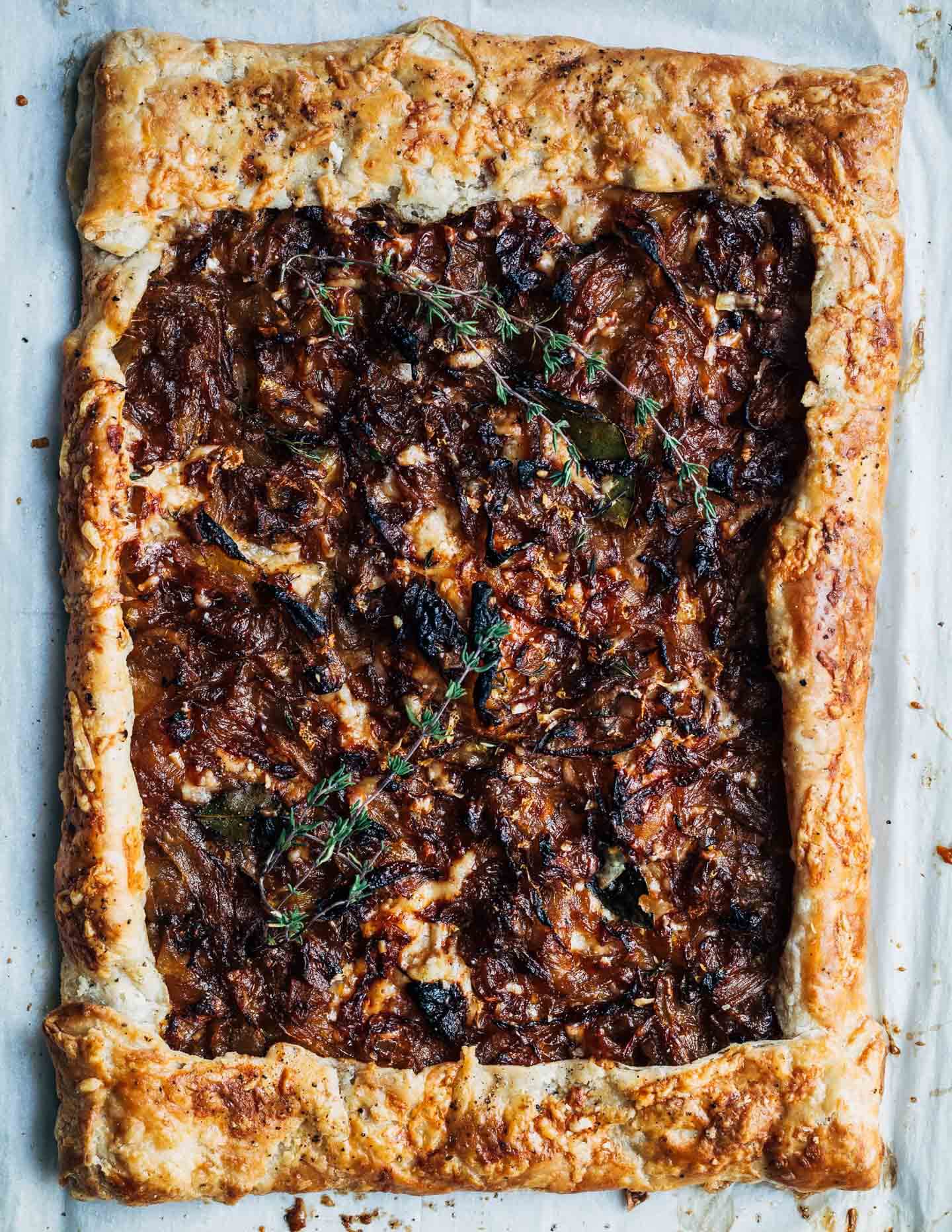 A caramelized onion tart on a parchment-lined baking sheet, just out of the oven. 