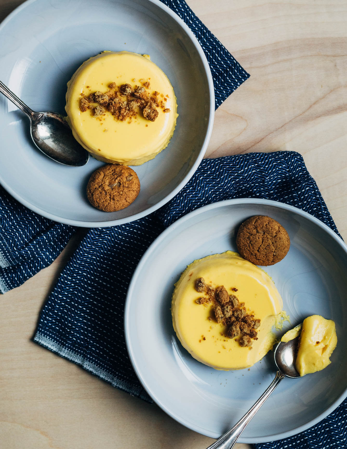 Two serving dishes with pumpkin panna cotta. They are topped with cookies crumbles and a cookie alongside. 