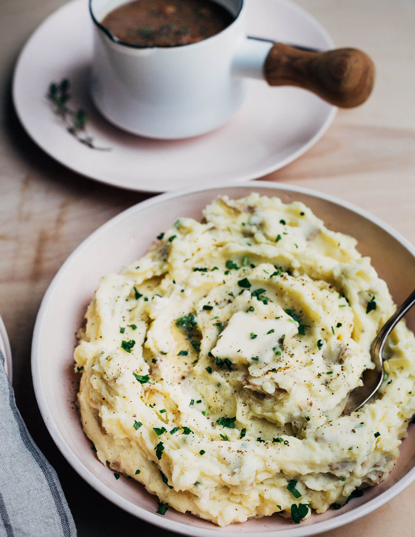 A table with a bowl of mashed potatoes, and a gravy dish.