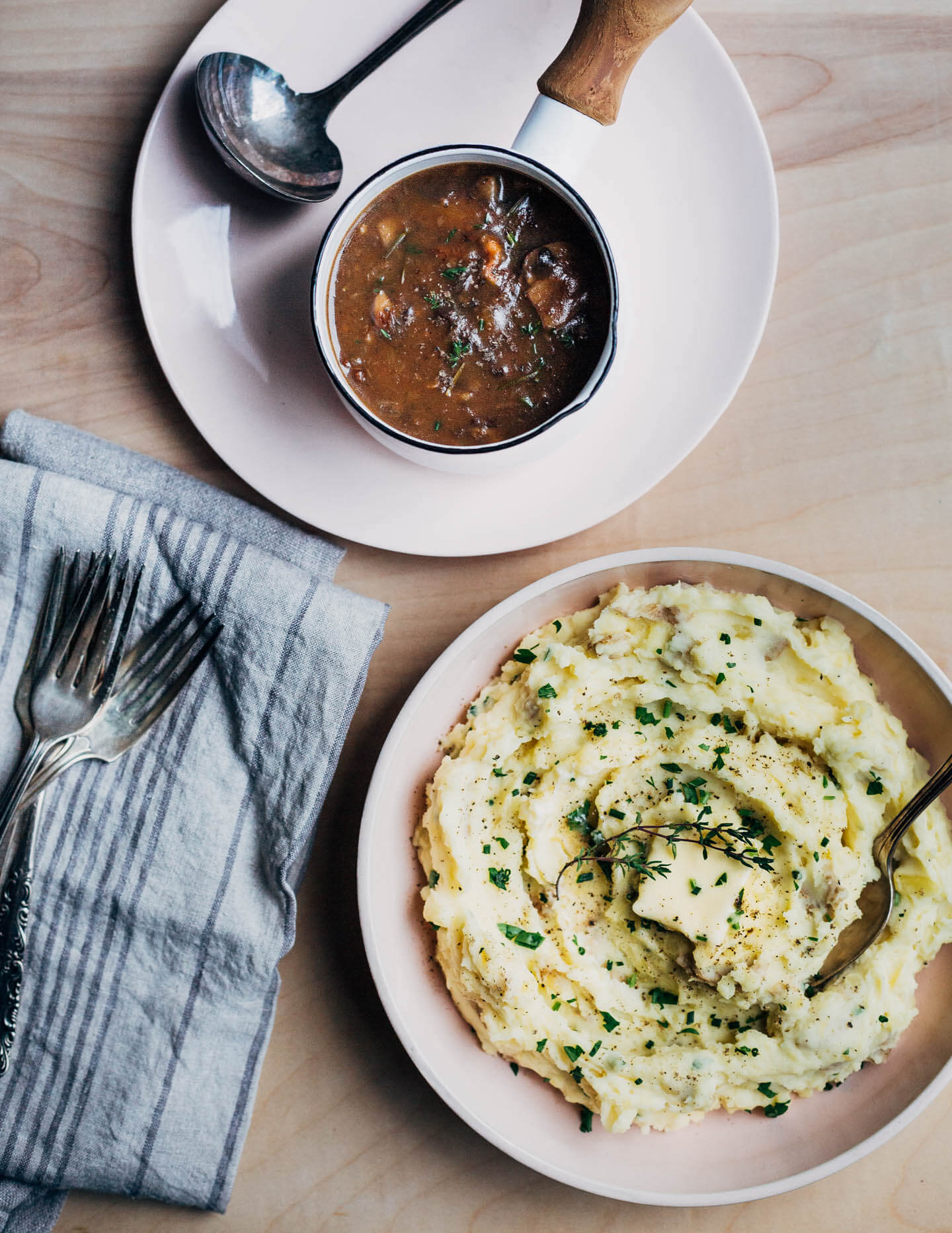 A table with a bowl of mashed potatoes, and a gravy dish. 