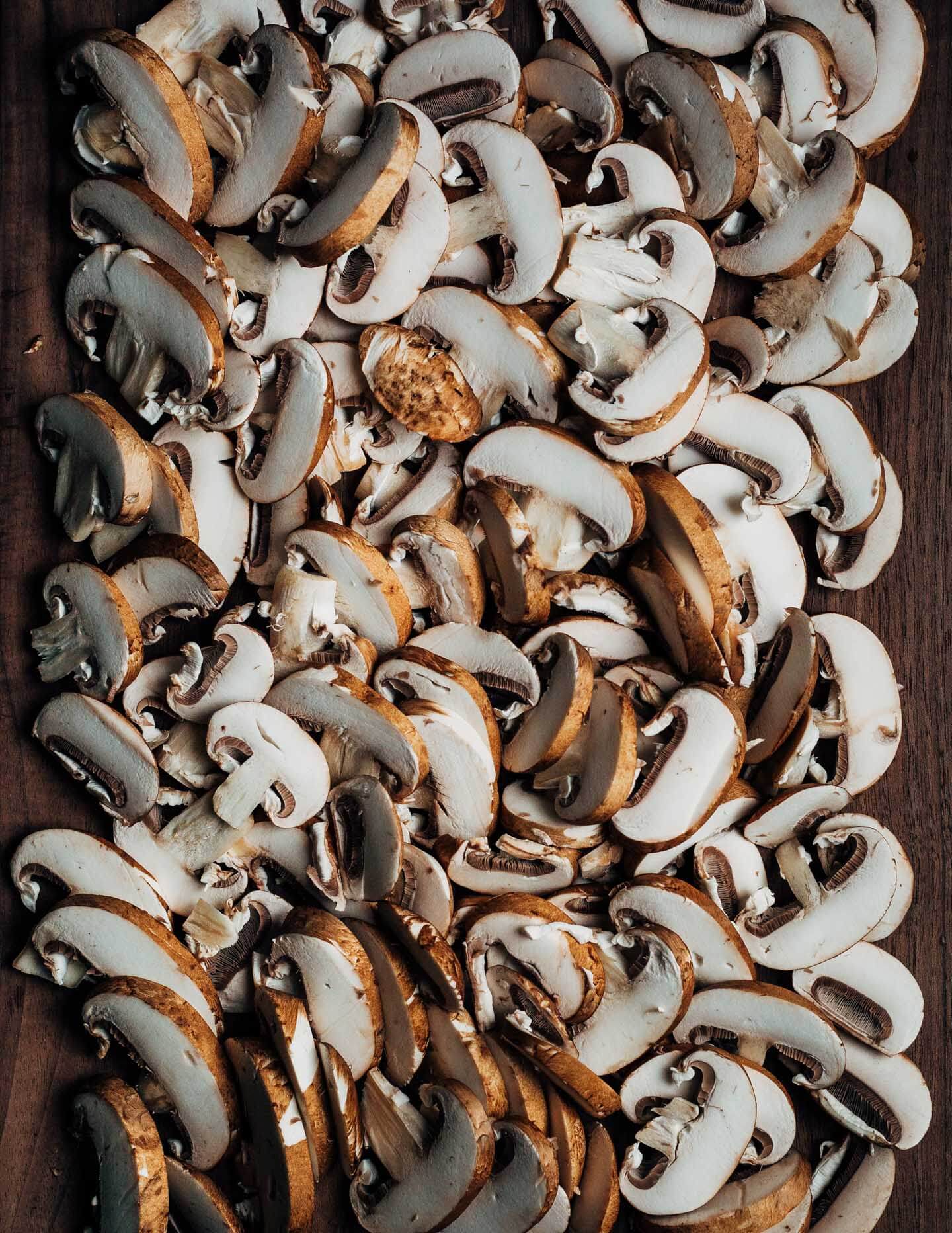A cutting board covered in sliced mushrooms.