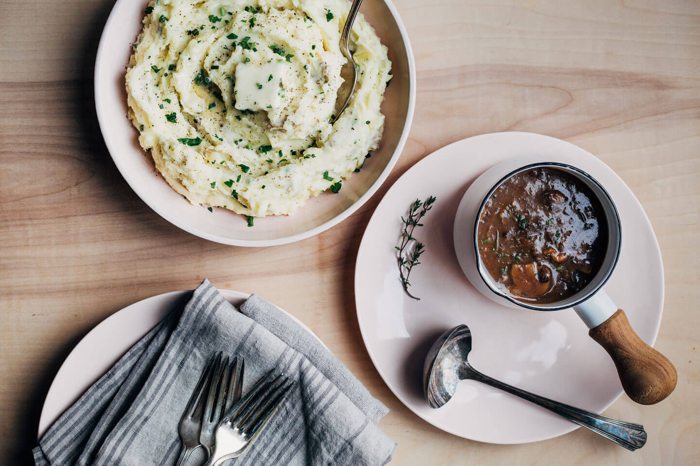 A bowl of mashed potatoes and a gravy boat on a table. 