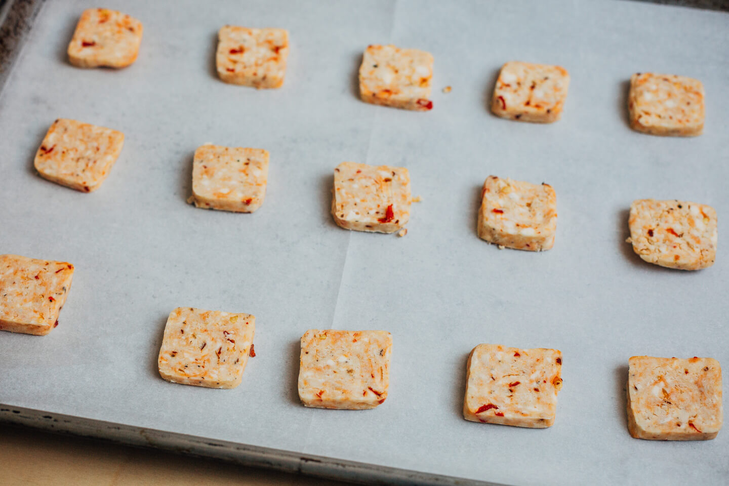 Unbaked cheddar crackers on a baking sheet.