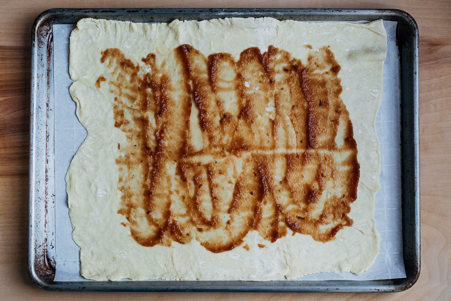 Pastry dough on a baking sheet spread with apple butter. 
