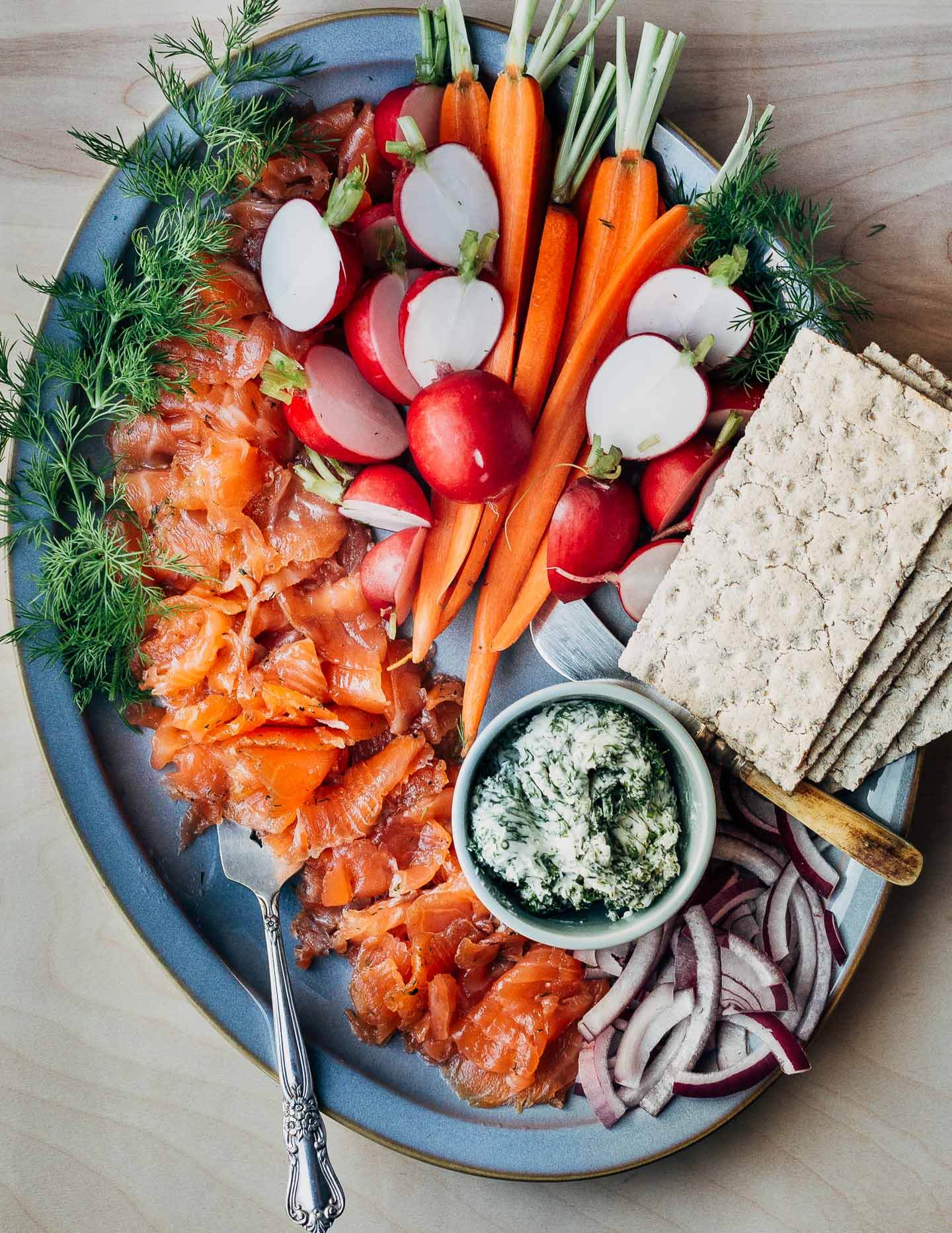 A platter of gravlax with crackers, carrots, radishes, and red onions. 