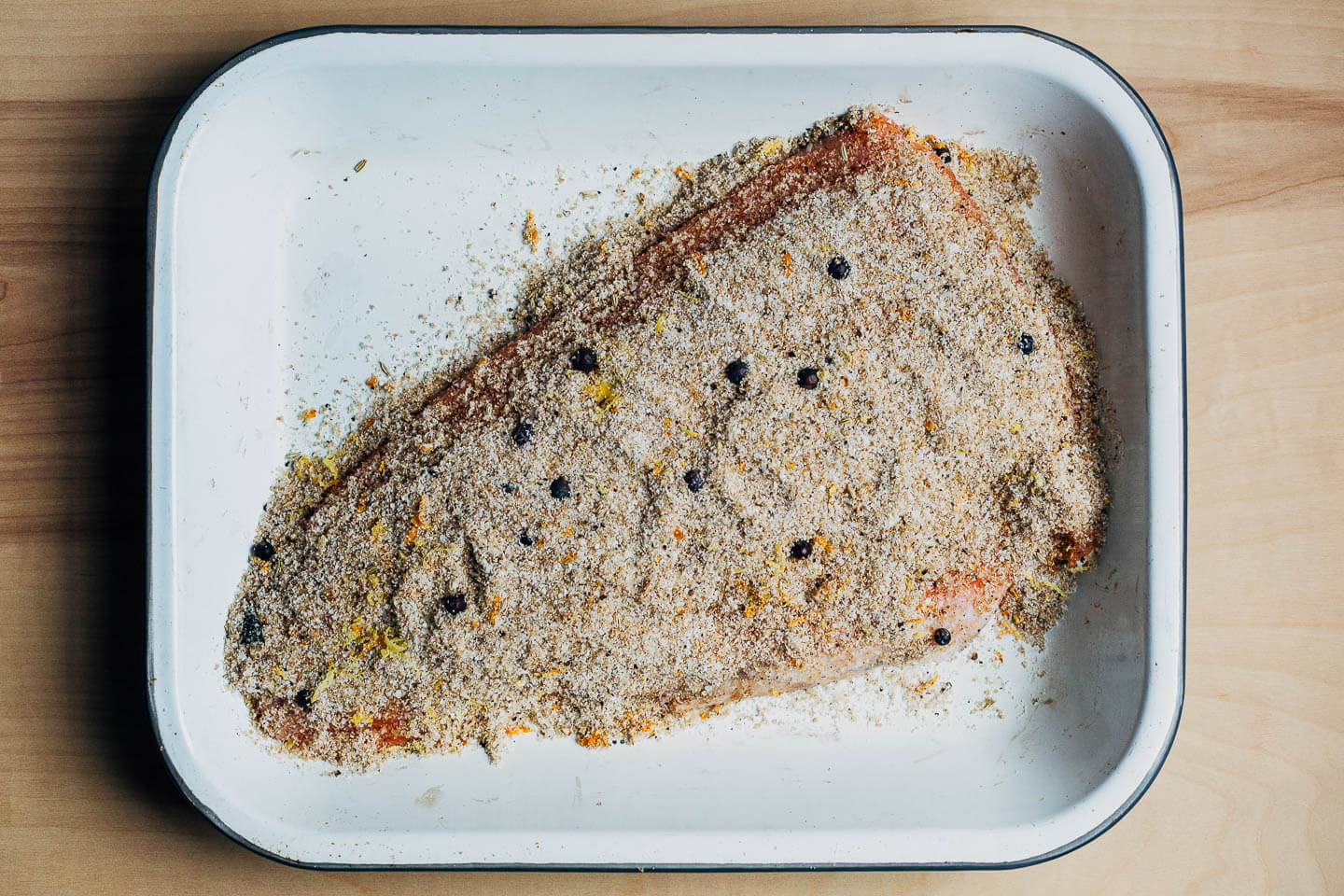 A salmon filet coated with a salt, sugar, and spice mixture for curing.