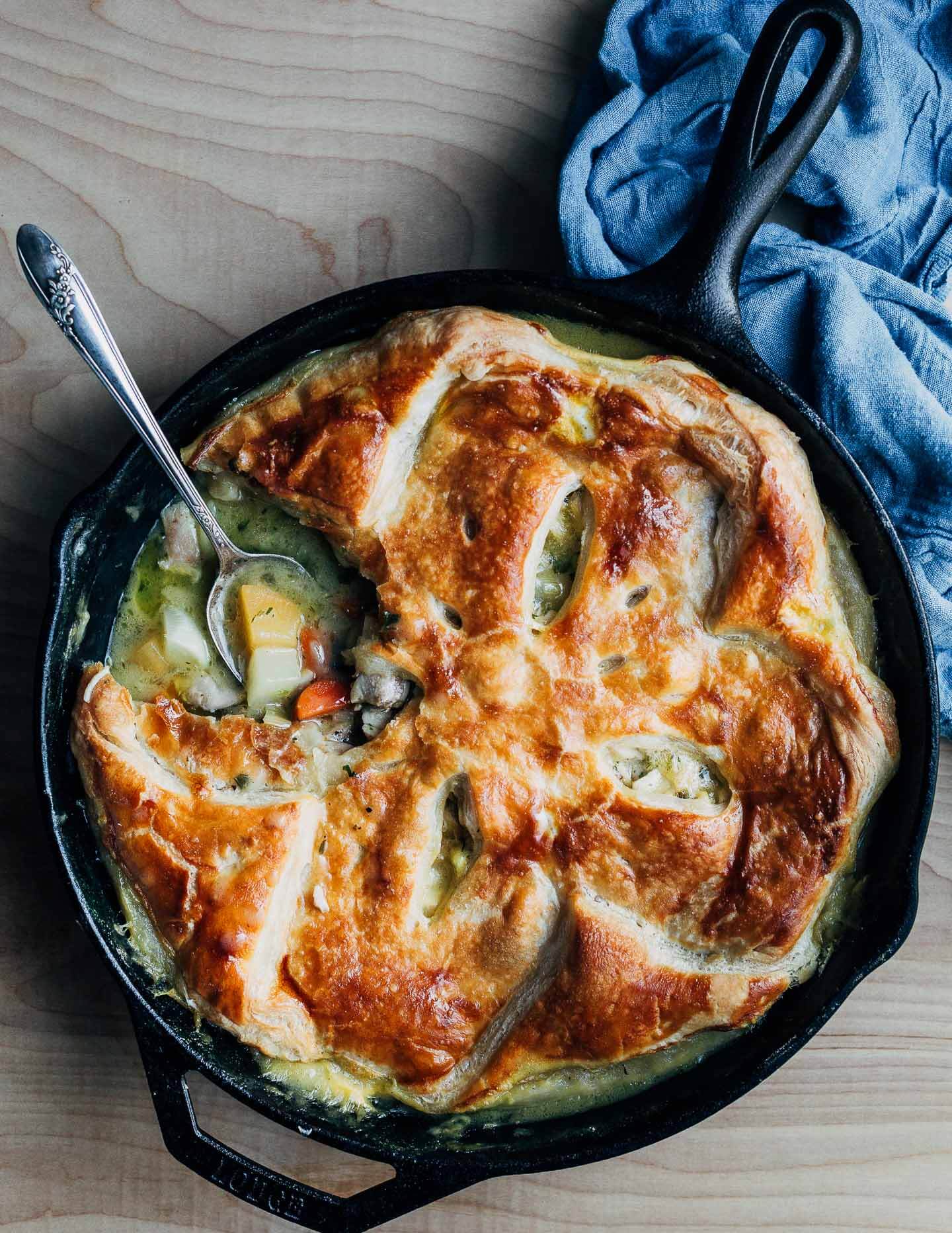 A skillet of chicken pot pie with a spoon getting a serving. 