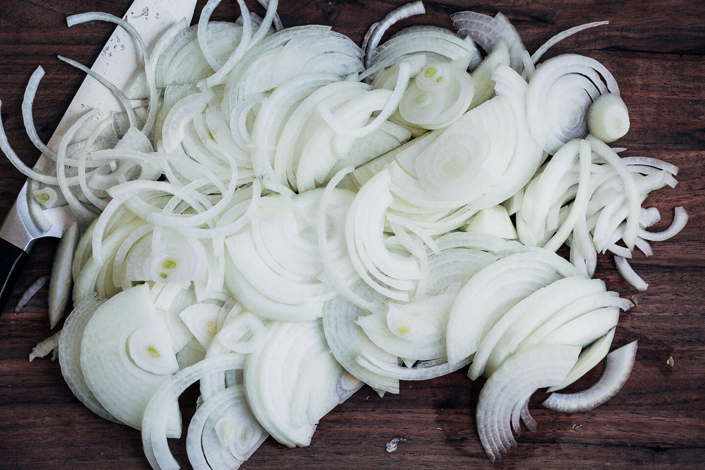 Sliced yellow onions on a cutting board.