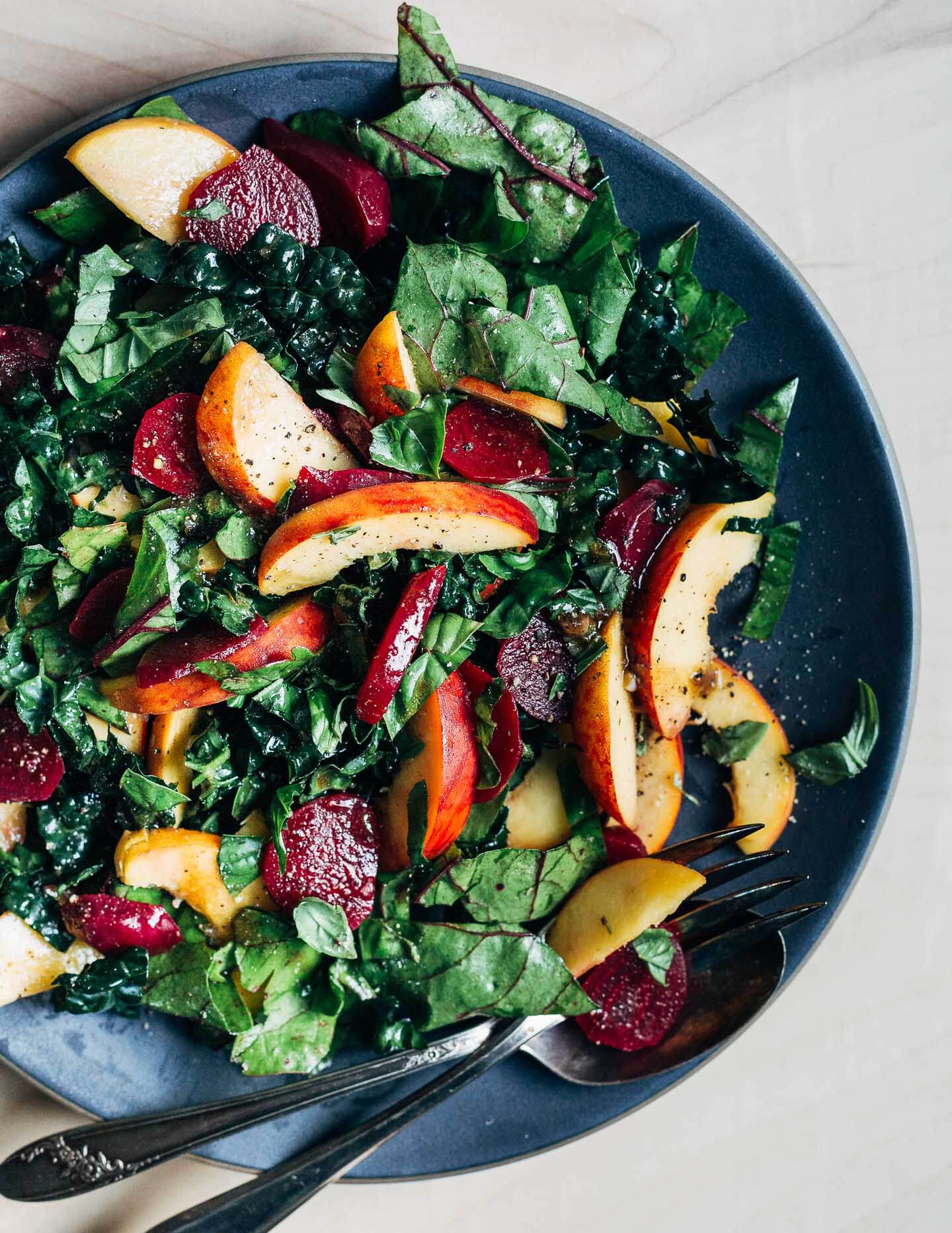 A platter with a tossed beet, peach, and greens salad.