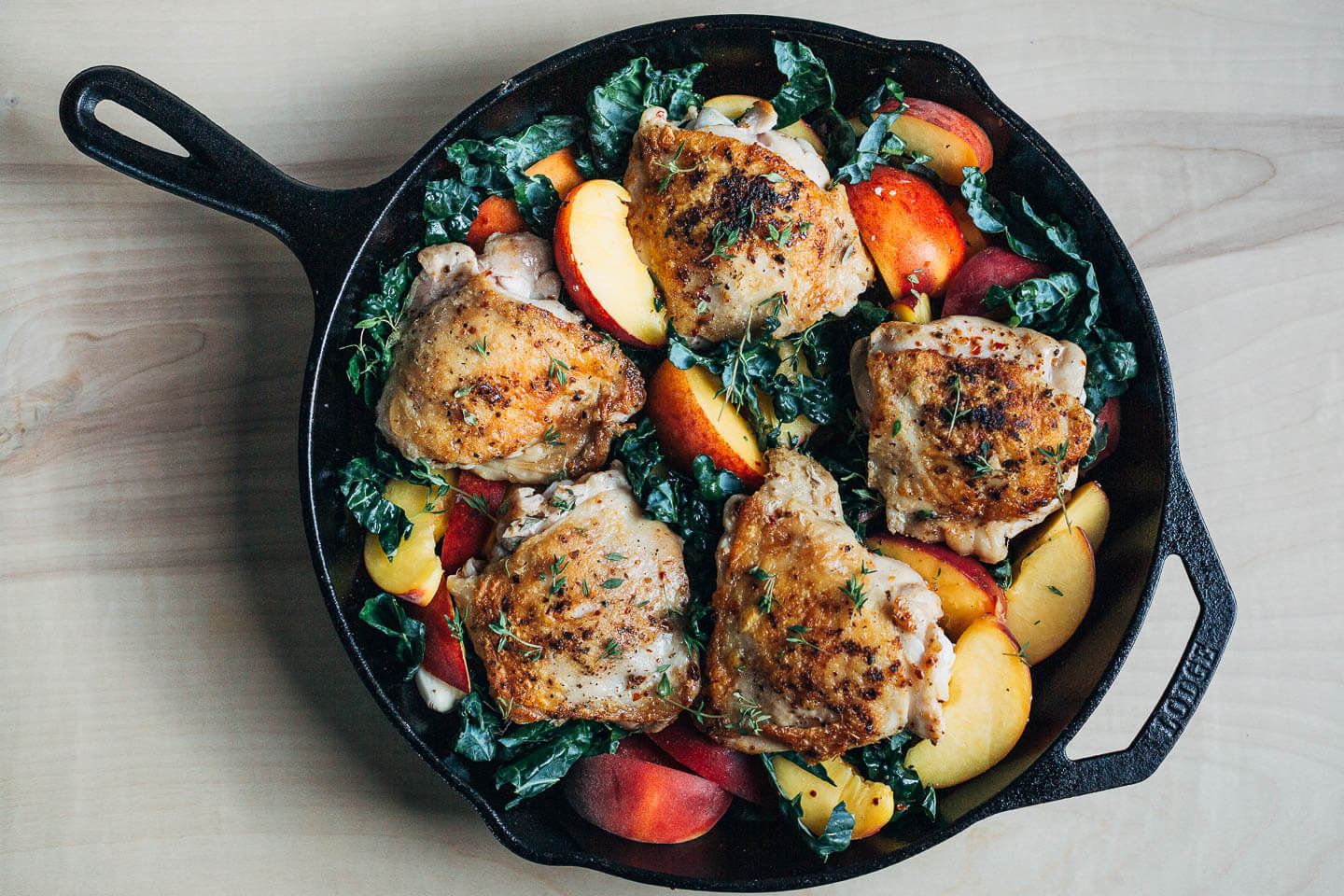 Seared chicken and peaches in a skillet, ready to bake