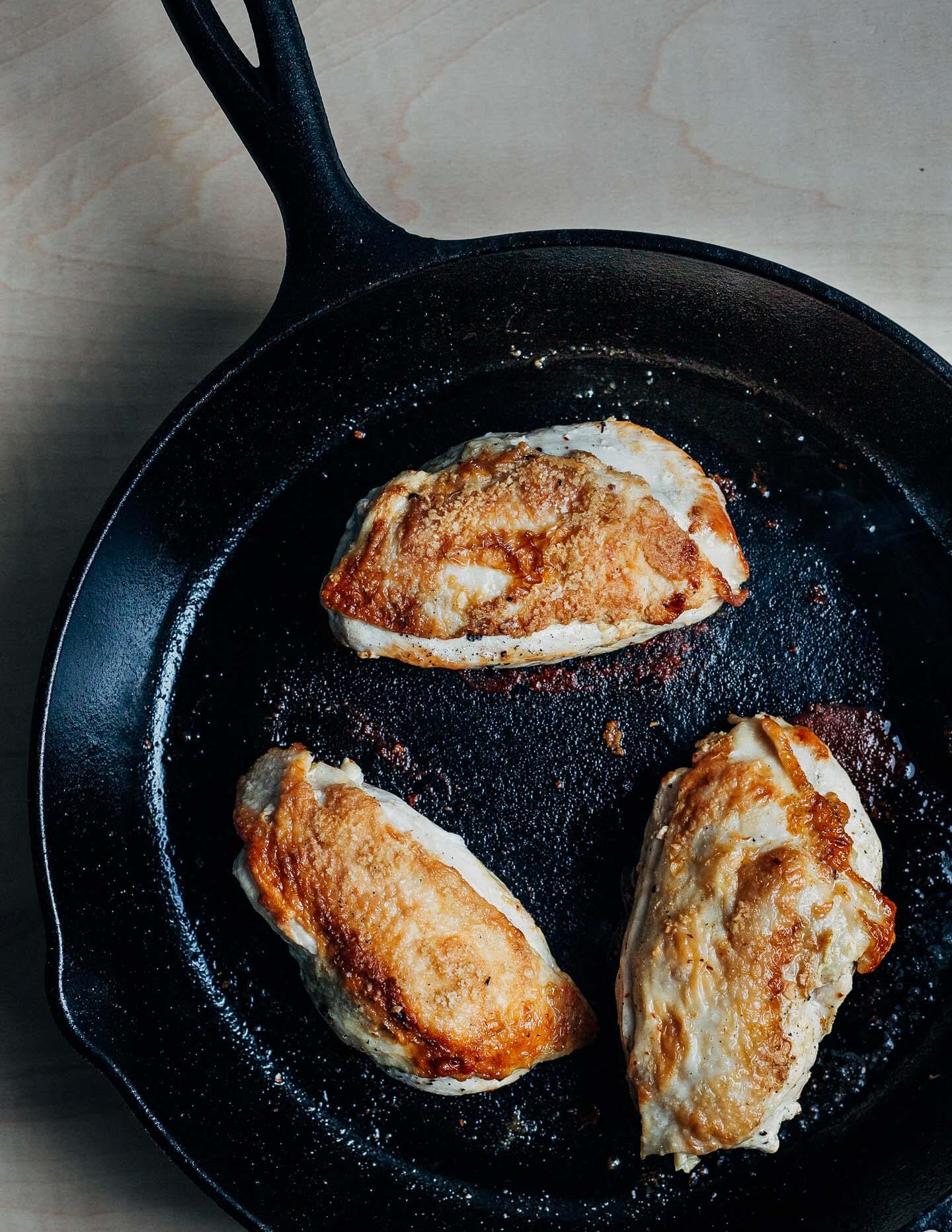 Chicken cooking in a cast iron skillet. 